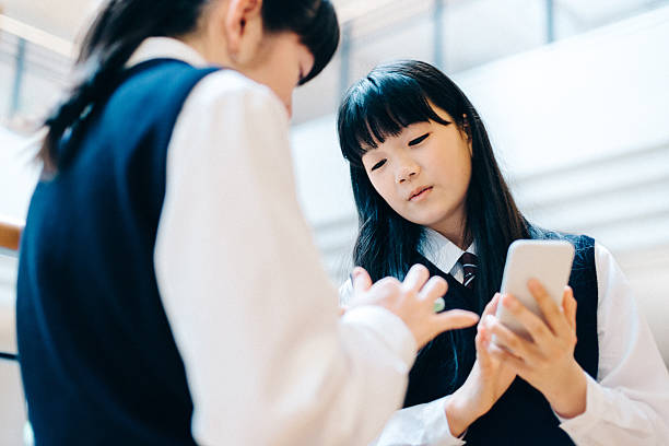 日本の高校の女の子がスマートフォンを使用しての学生の学校 - japanese culture asian ethnicity friendship computer ストックフォトと画像