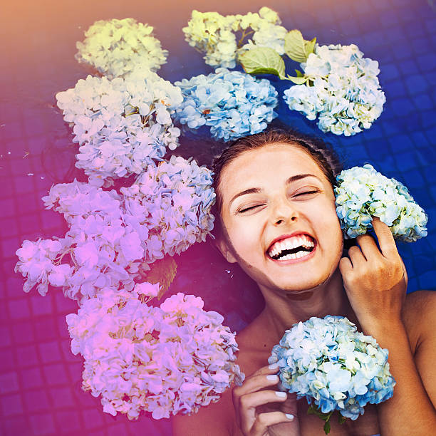 dramatic portrait of a woman floating an a swimming pool full of flowers (macro)