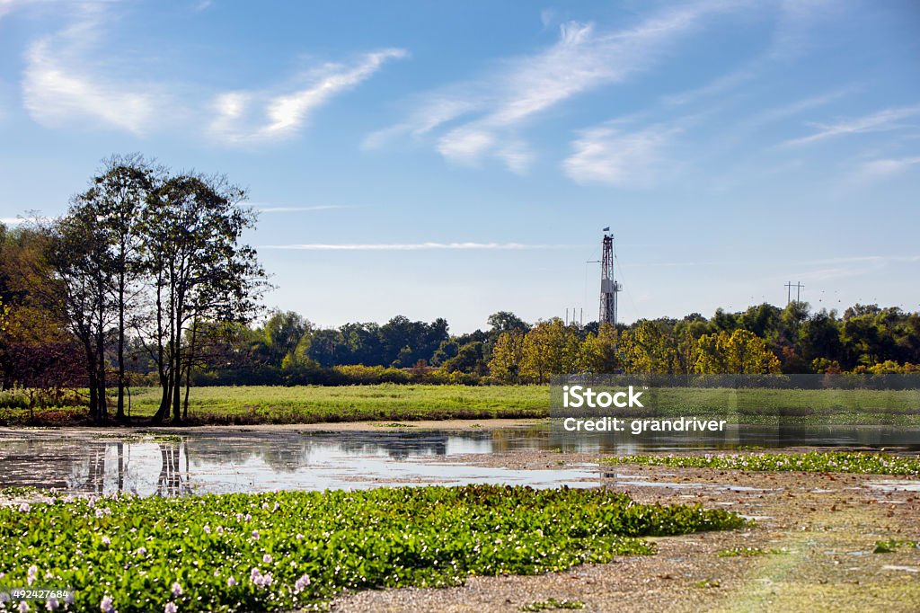 Fracking Drilling Rig Near a Louisiana Bayou Pristine landscape of a lilly pad swamp in the deep south of the United States Louisiana with a Drilling Rig fracking operation occuring. Louisiana Stock Photo