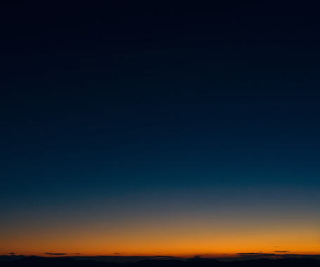 Dark blue sky above the orange glow above a distant horizon at dusk.