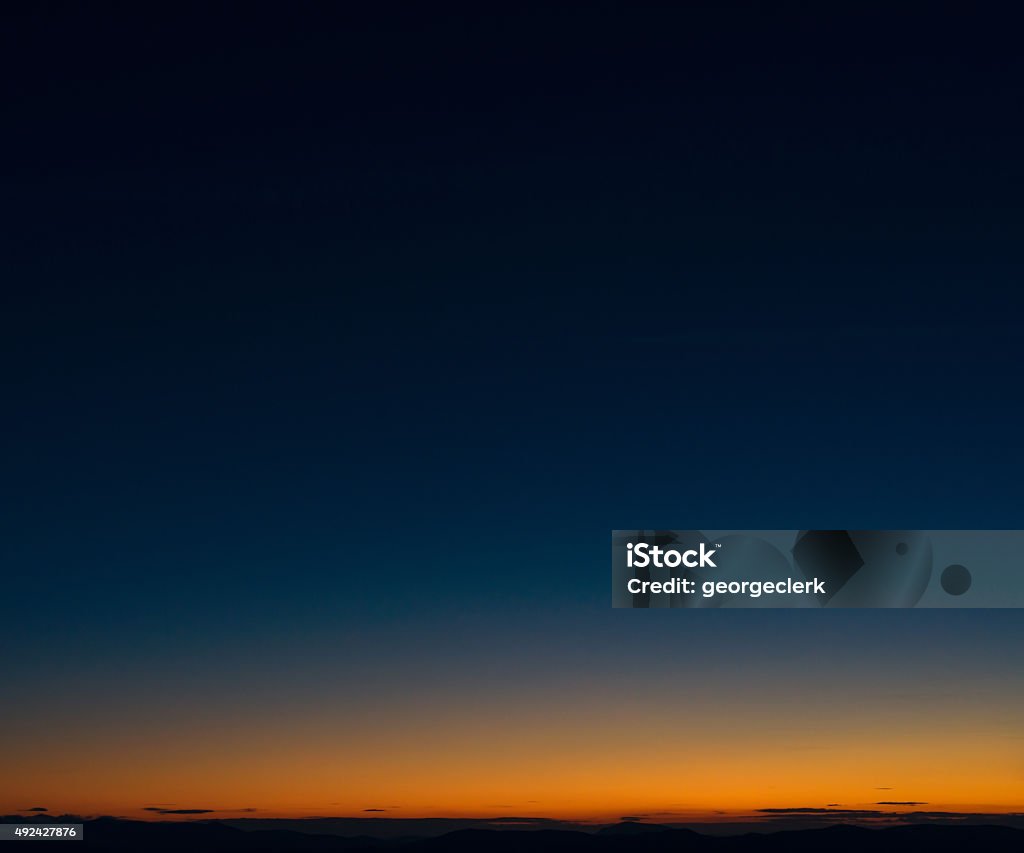 Dusk horizon sky Dark blue sky above the orange glow above a distant horizon at dusk. Sky Stock Photo