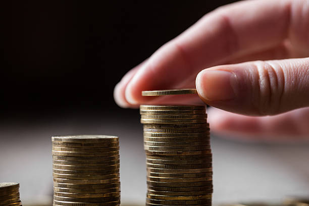 istock Hand putting coins to a stack on a wooden background 492428764