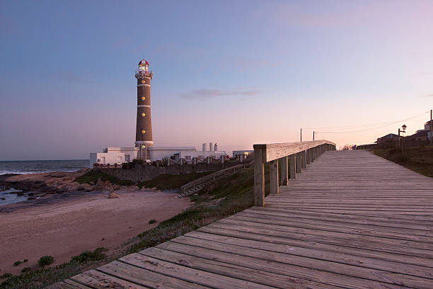 Lighthouse in Punta del Este at sunset View of Jose Ignacio lighthouse in Punta del Este during  a beautiful sunset with wooden promenade in the foreground and beach at the side. uruguay photos stock pictures, royalty-free photos & images