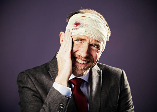 istock Wincing businessman with bandaged, bloody head 492440073