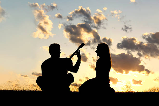 シルエットカップルがギターを弾いている夕暮れ - copy space isolated women joy ストックフォトと画像