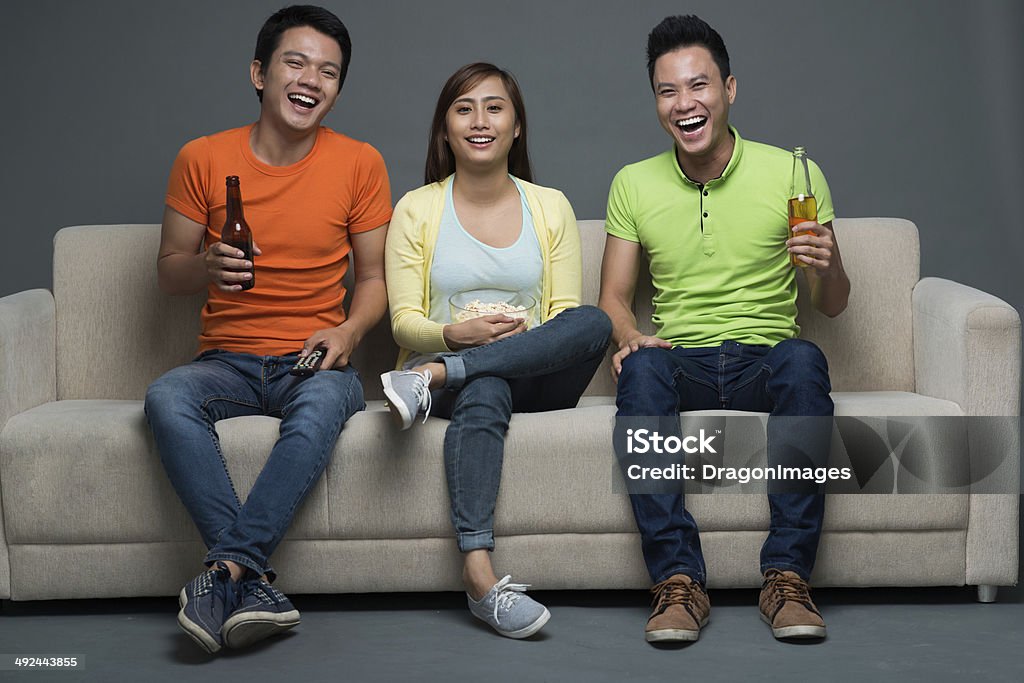 Vietnamese friends Vietnamese friends sitting on couch and watching tv Adult Stock Photo