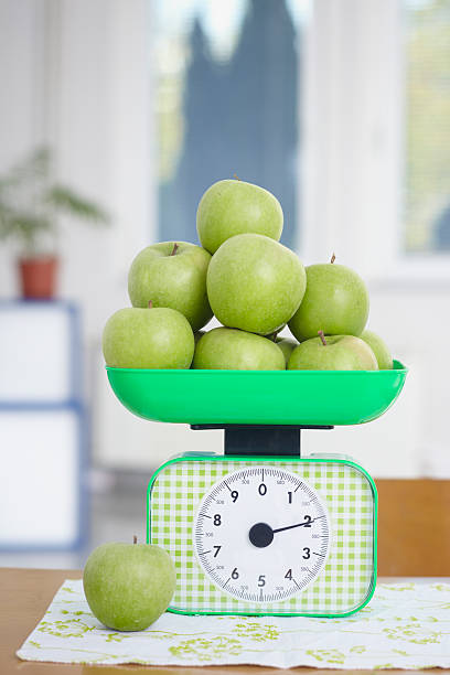 maçã verde na balança de cozinha comida de frutas - weight scale apple comparison balance - fotografias e filmes do acervo