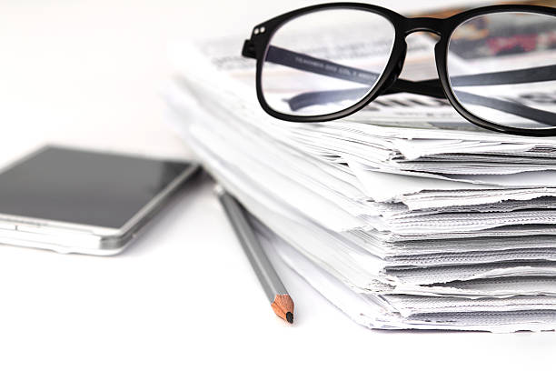 istock reading eyeglasses with stacking of newspaper background , busin 492449998