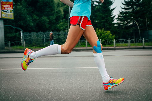 Omsk, Russia -  September 20, 2015: girl athlete running a marathon, knees in blue kinesiology taping during Siberian international marathon
