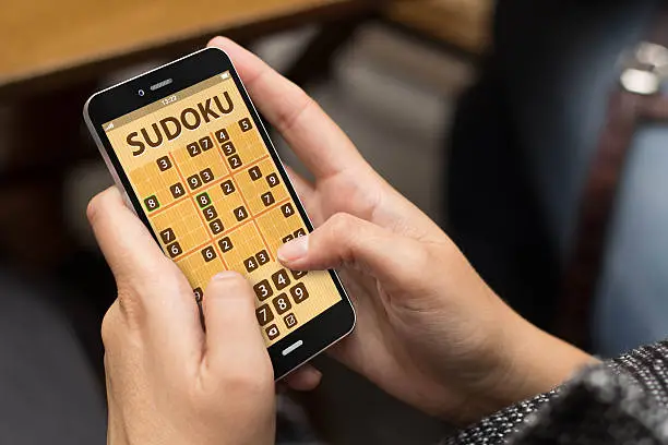 woman playing sudoku game at smartphone
