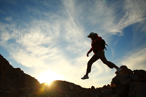 \nFemale hiker jumping from a rock at sunset. \n \n\n\n\n \n