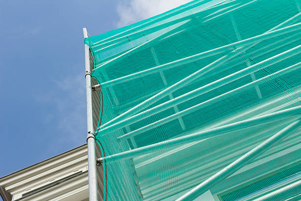 Green safety netting during restoration Scaffolding and green safety netting during the restauration of a building in the city. safety net stock pictures, royalty-free photos & images