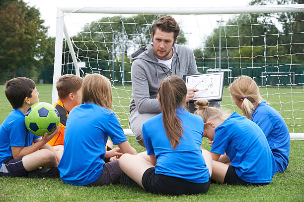 entrenador personal que habla de escuela primaria del equipo de fútbol - soccer child coach childhood fotografías e imágenes de stock