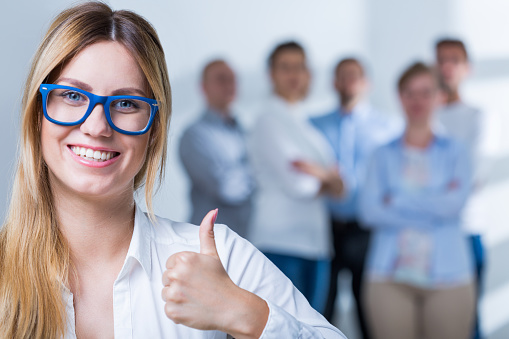 Smiling businesswoman with spectacles showing thumb up