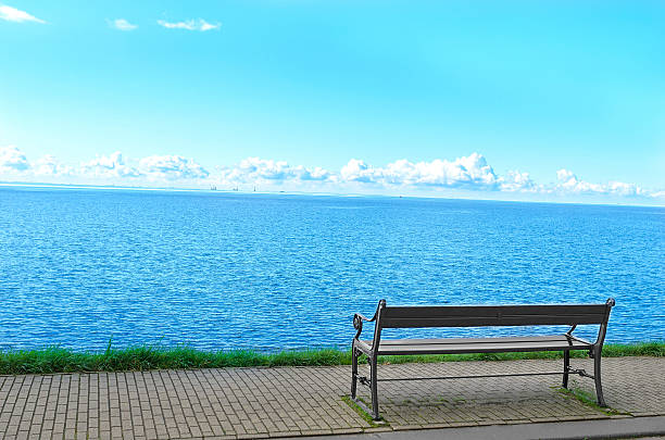 Overweight young woman sitting on a bench by the sea watching the view