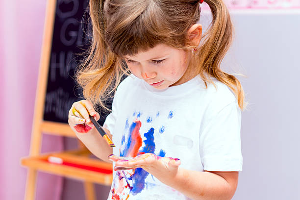 istock Little beautiful girl draws paints. 492464728