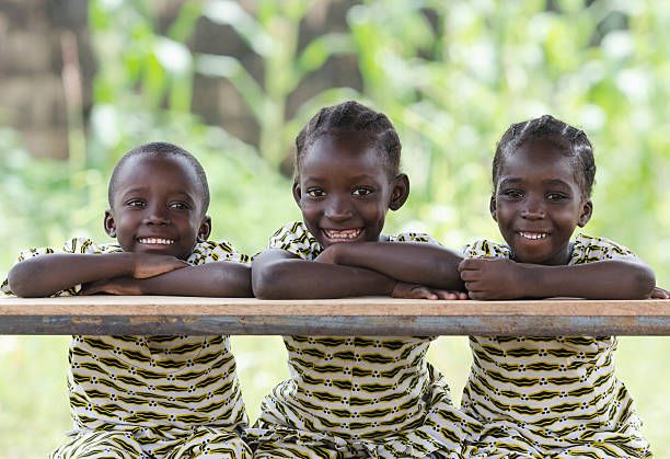 três crianças africanas na escola educação símbolo aluna aluno sentado - áfrica ocidental imagens e fotografias de stock