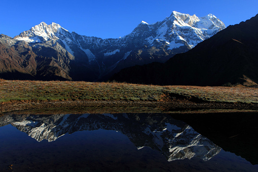 Reflection of snow-capped peaks of the himalayas caught in a lake shot at uttarakhand,india.