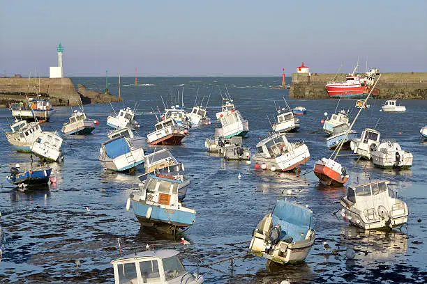 Boats at low tide and lighthouse in the port of Barfleur, a commune in the peninsula of Cotentin in the Manche department in Lower Normandy in north-western France