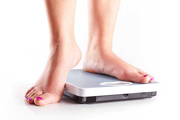 istock Pair of female feet on a bathroom scale 492493915