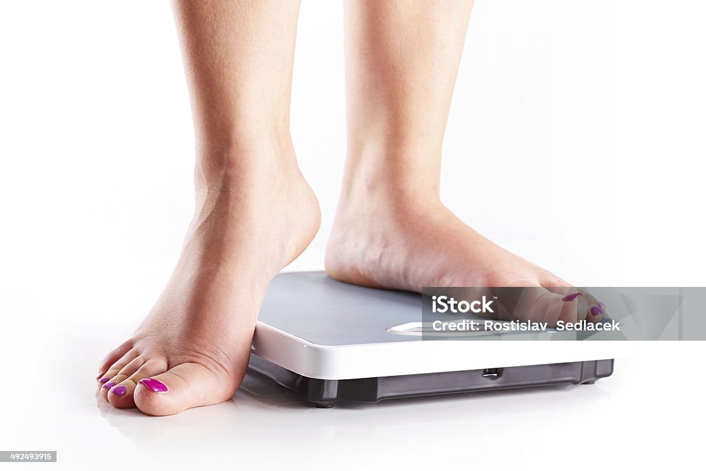 Pair of female feet on a bathroom scale A pair of female feet standing on a bathroom scale Adhesive Tape Stock Photo