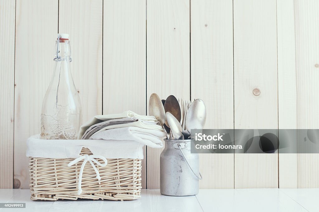 Home kitchen decor Home decor: glass bottle and wicker basket and vintage cutlery on a wooden board background, cozy kitchen arrangement in retro style, soft pastel colors. Apartment Stock Photo