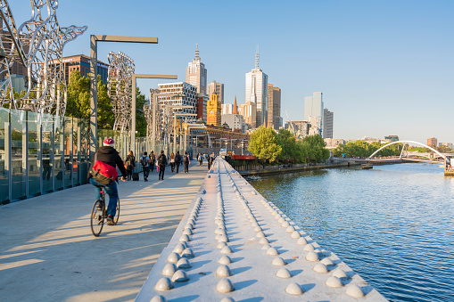 Melbourne, Australia - Oct 8, 2015: Cyclist and people walking across a bridge in downtown Melbourne at sunset