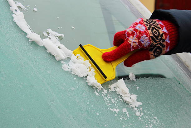 hand der frau eis vom auto-windschutzscheibe abschaben - frozen windshield cold car stock-fotos und bilder