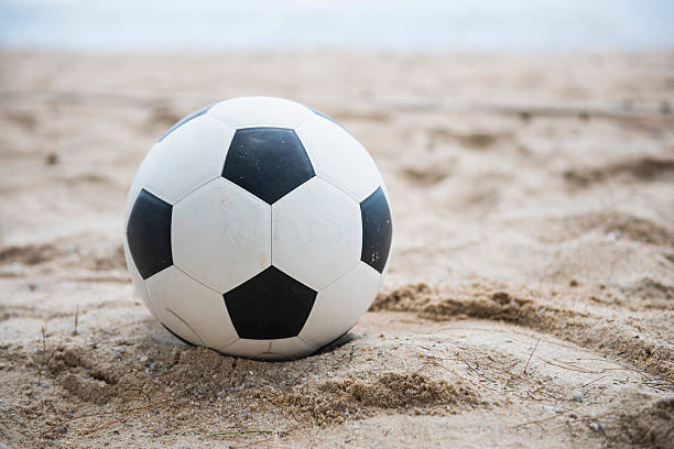 istock football on sand beach 492513396