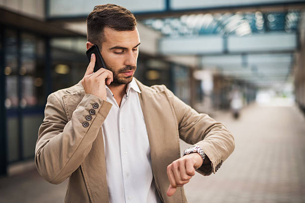 homme d'affaires sur le téléphone vérifier l'heure. - vérifier lheure photos et images de collection