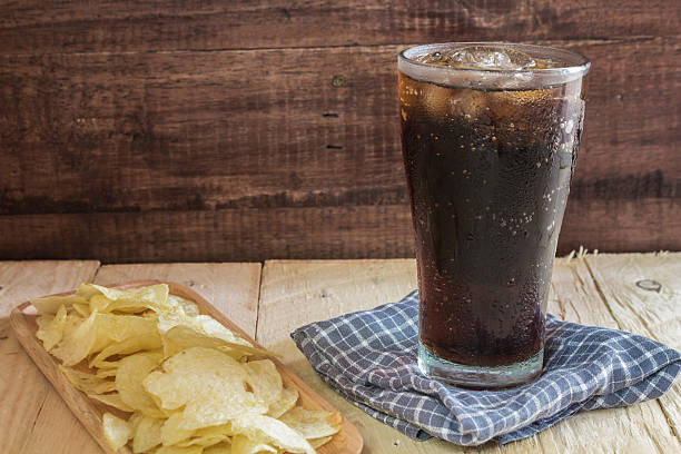 istock cola in glass and potato chips  on wooden background. 492521744