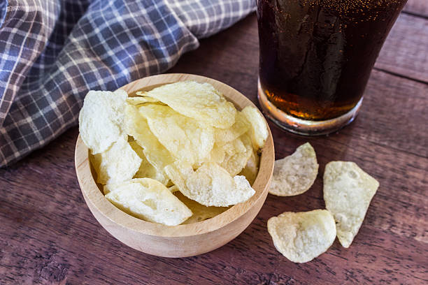 istock potato chips and cola in glass  on wooden table. 492522624