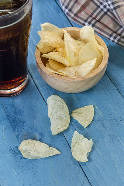 istock potato chips and cola in glass  on wooden table. 492522988