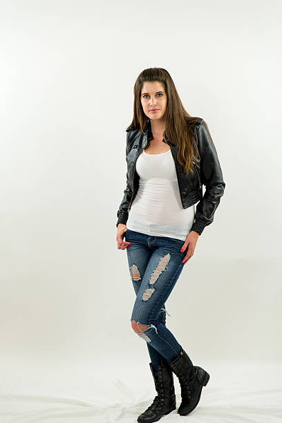 istock Woman in leather jacket, jeans and t-shirt standing looking forward 492531113