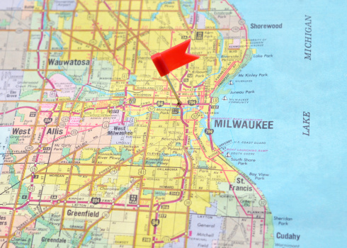Close up of a flag pin marking Milwaukee, Wisconsin on an old, generic map.  