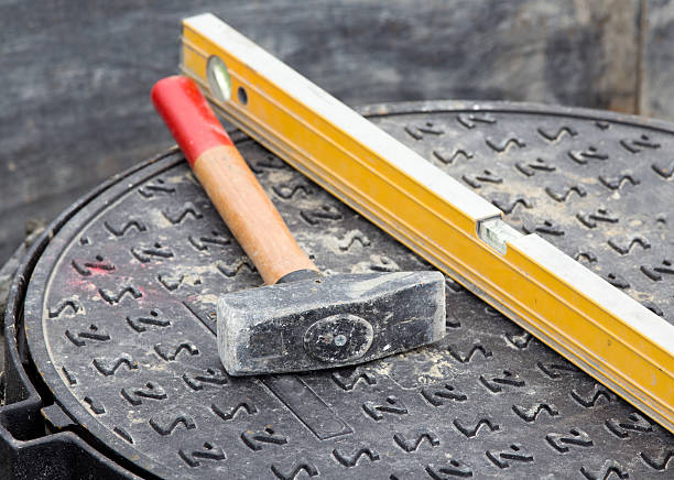 istock Hammer and level on manhole cover 492537604