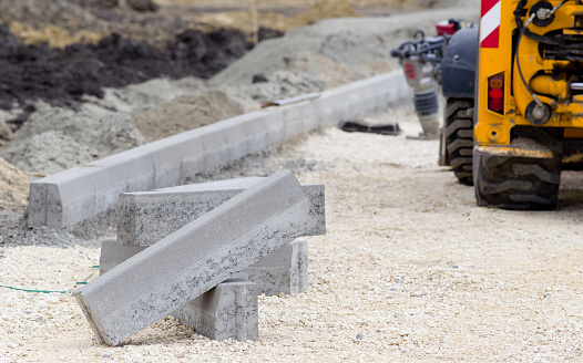 Kerb stones on gravel ground for placing road edge at construction site