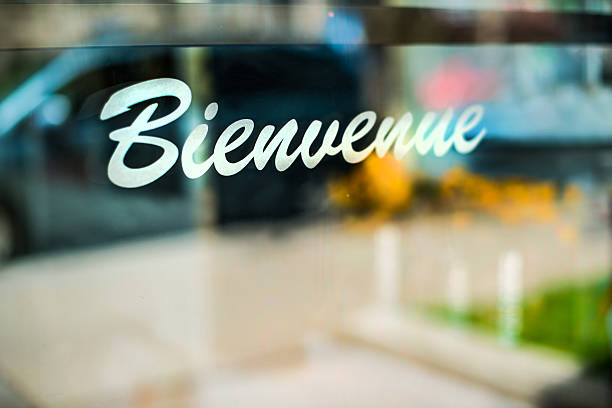 Welcome Bienvenue sign on  entrance door with reflections of the street french language photos stock pictures, royalty-free photos & images