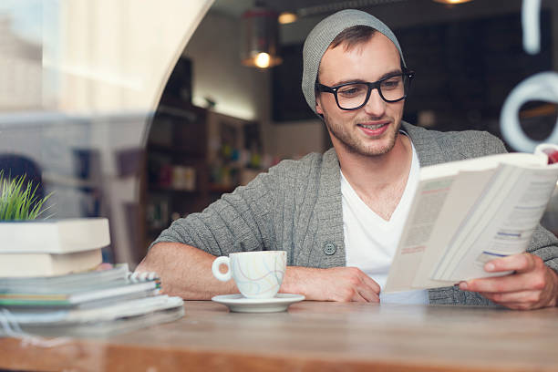 istock Smiling hipster man reading book at cafe 492543481