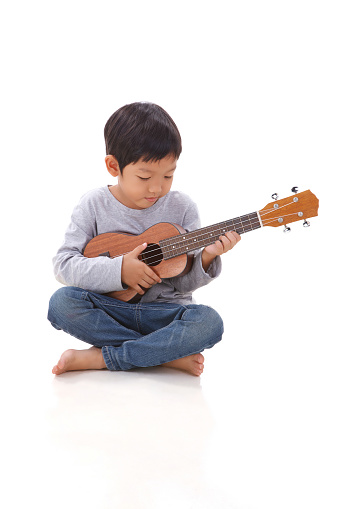 little boy playing the ukulele