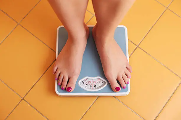 A pair of female feet standing on a bathroom scale