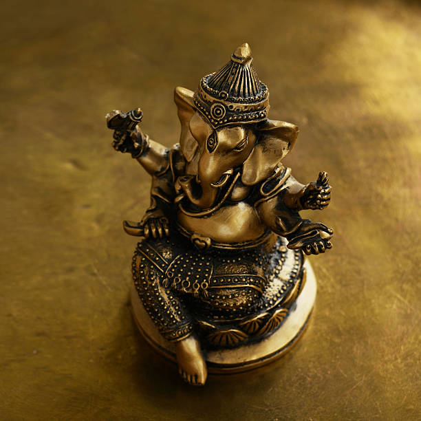 istock Ganesh bronze statuette over golden background 492545328