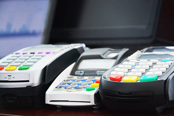 payment central three different payment terminals next to comupter that displays statistics exchange teller stock pictures, royalty-free photos & images
