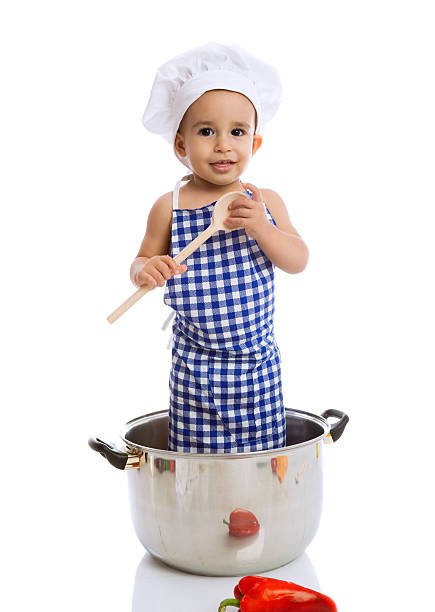 istock Child chef holding scoop and standing in pot 492547240