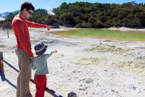 family of two looking at colorful hot spring at the north island in new zealand
