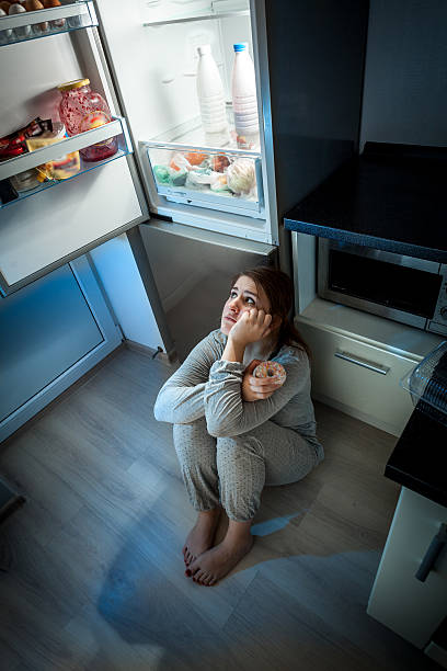 istock woman sitting on floor and looking at fridge at night 492548277