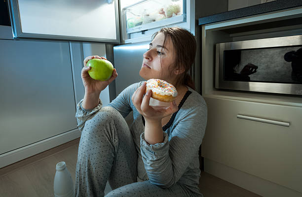 женщина, выбирая между apple и пончик на обед вечером - apple women green eating стоковые фото и изображения