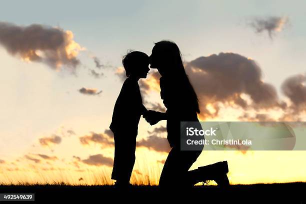 Mother Lovingly Kissing Little Child At Sunset Stock Photo - Download Image Now - Mother, Child, In Silhouette