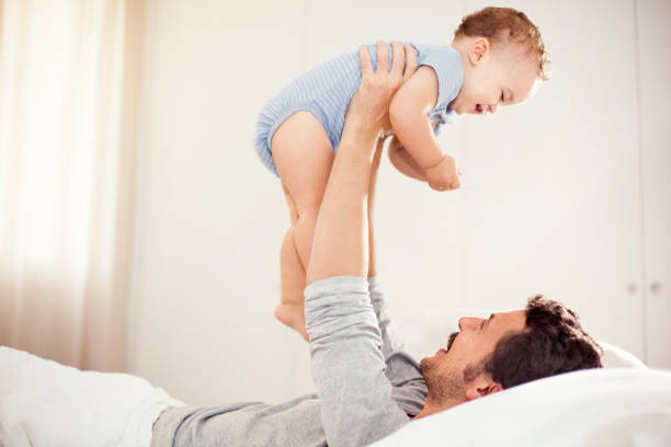 istock Father playing with baby son on bed 492549768