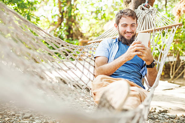 istock caucasian man lying in hammock with mobile phone 492549966